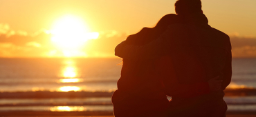 Arm in Arm am Strand dem Sonnenuntergang zuschauen
